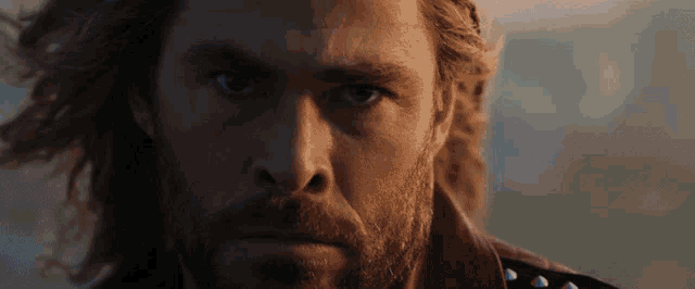 a close up of a man 's face with a beard and long hair