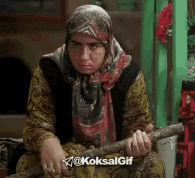 a woman in a head scarf is holding a stick .