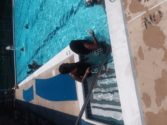 a woman sits on the edge of a swimming pool with the number 4 on the side