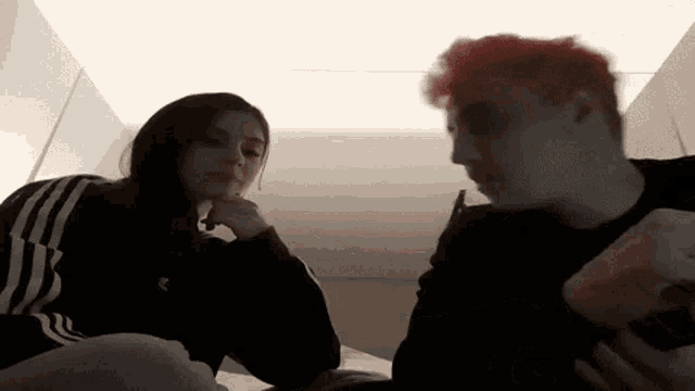 a man and a woman are sitting next to each other in a room . the woman has red hair .