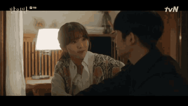 a man and a woman are looking at each other with the tvn logo behind them