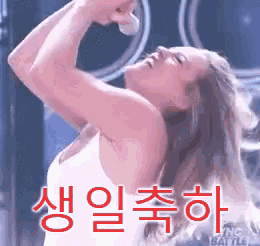 a woman singing into a microphone with korean writing on the bottom right