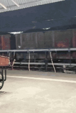 a train is parked in a warehouse with a wheelbarrow