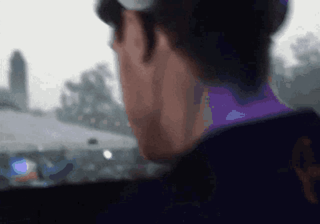 a man wearing headphones looks out of a window