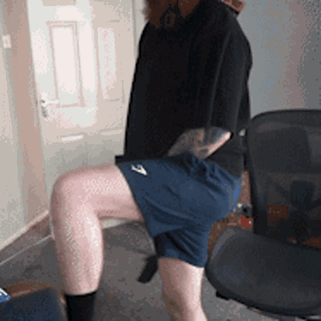 a man with a tattoo on his back is kneeling down