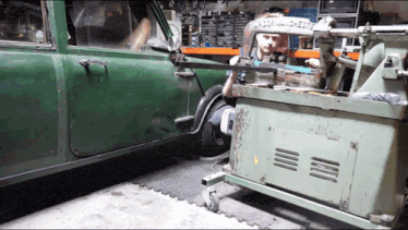 a green car is being worked on by a man in a garage