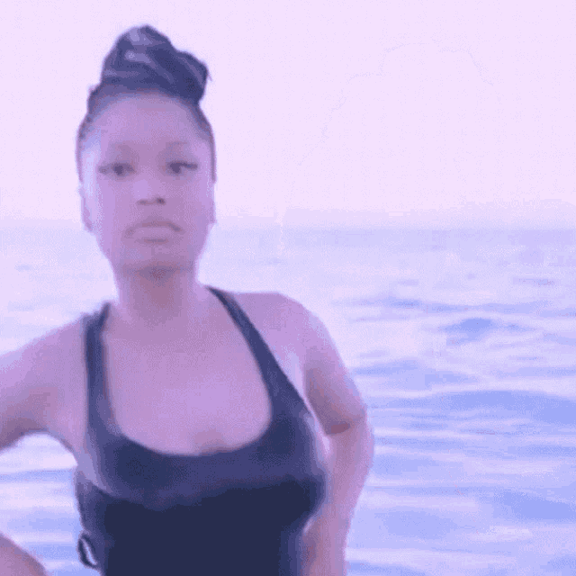 a woman in a bathing suit is standing in the ocean .