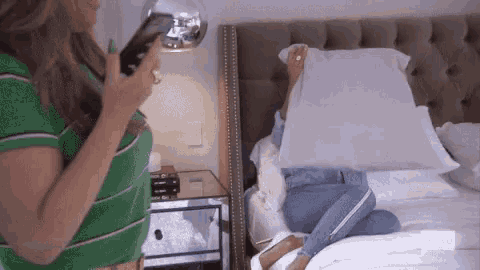 a woman in a green striped shirt is standing next to a bed with bravo written on the bottom
