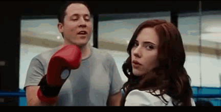 a man wearing boxing gloves is hitting a woman in the face in a boxing ring .