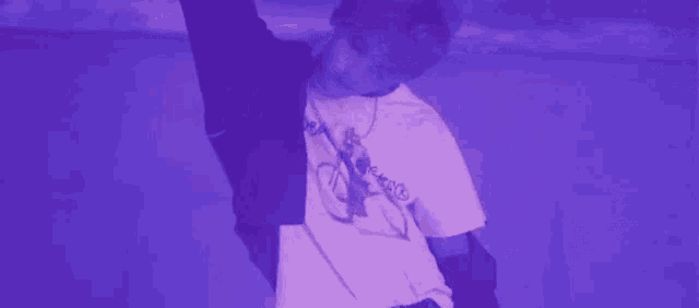 a man in a purple shirt is standing in front of a purple wall .