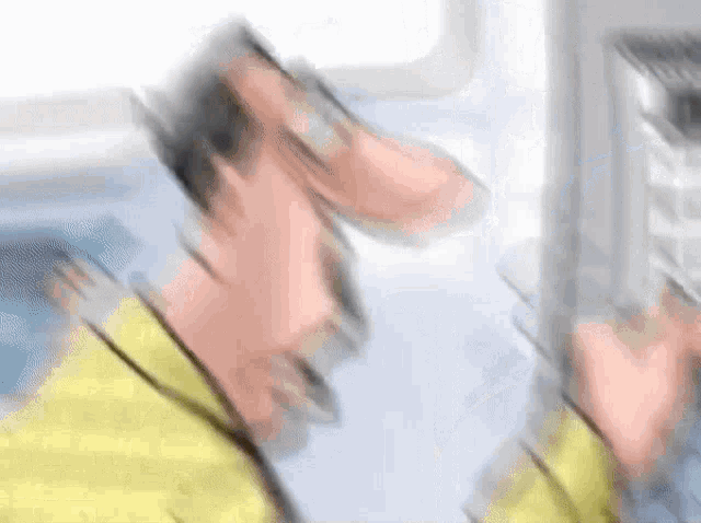 a blurry picture of a man in a yellow jacket talking on a phone