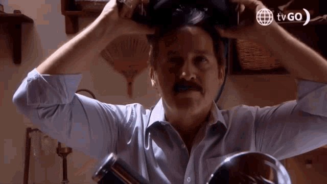 a man with a mustache is brushing his hair in a tv go ad