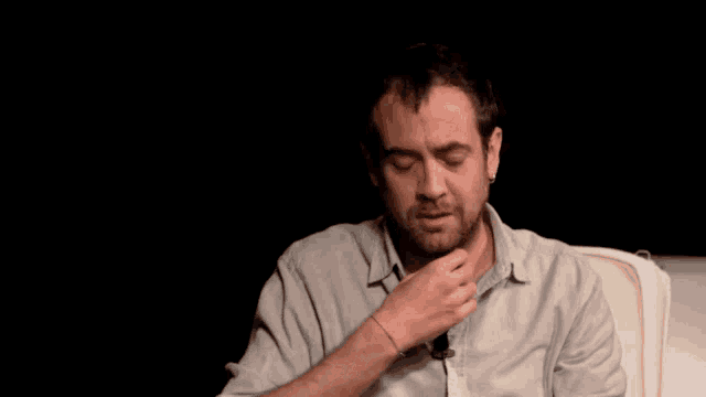 a man with a tattoo on his wrist covering his mouth with his hand