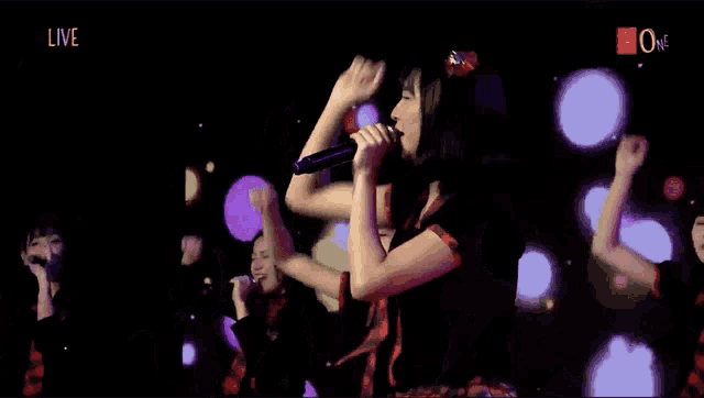 a woman singing into a microphone with the word live in the corner