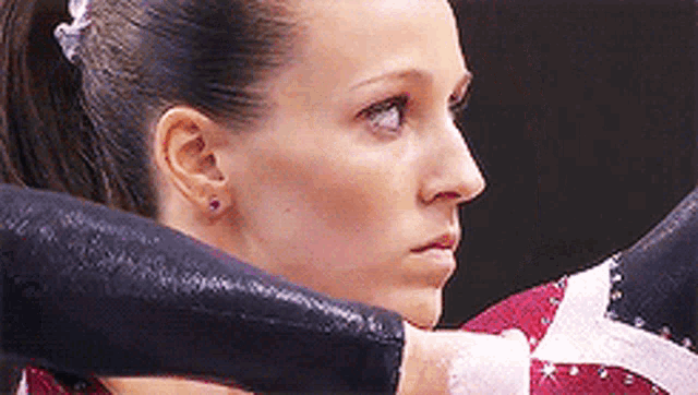 a close up of a woman 's face with a ponytail and earrings