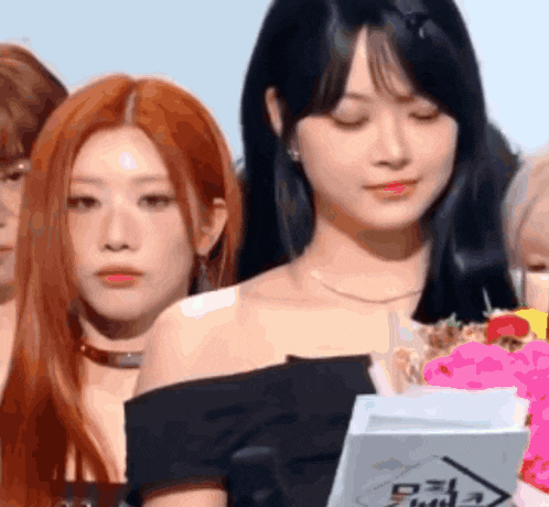 a group of women are standing next to each other and one of them has a bouquet of flowers in her hand .