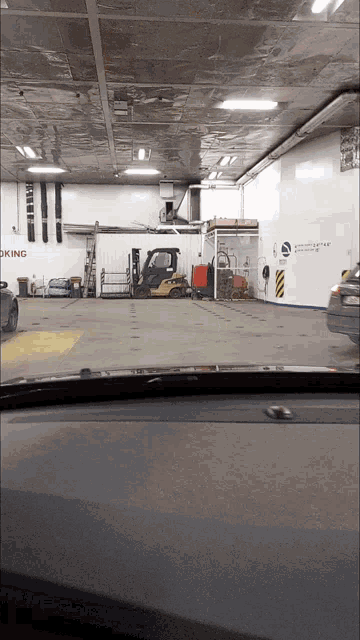 a forklift is parked in a parking garage with a sign that says no smoking