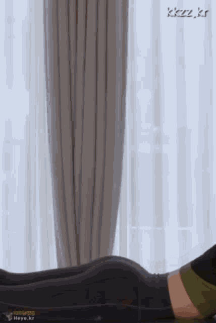 a woman is laying on a bed in front of a window .
