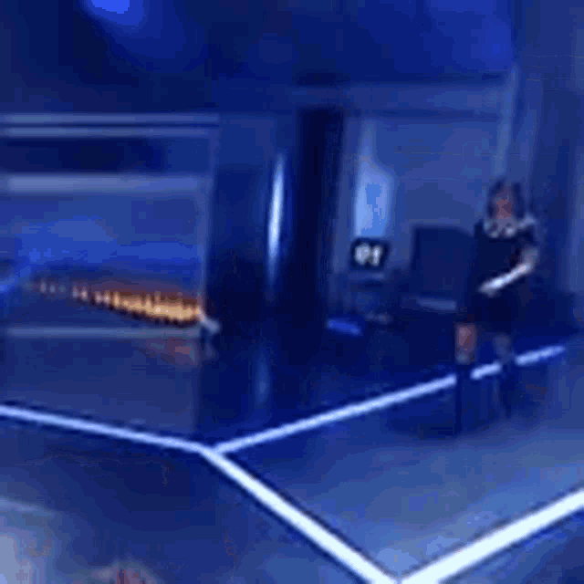 a woman in a black dress is walking on a stage in front of a blue background .