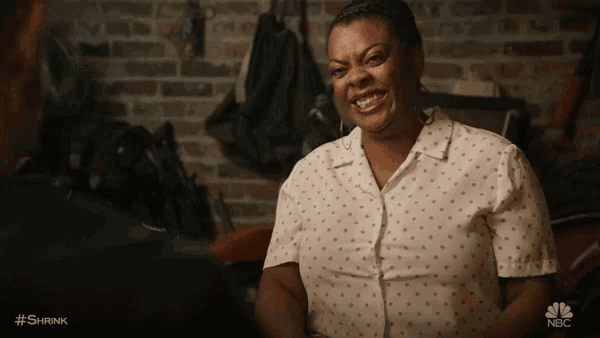 a woman in a polka dot shirt is smiling in a garage .