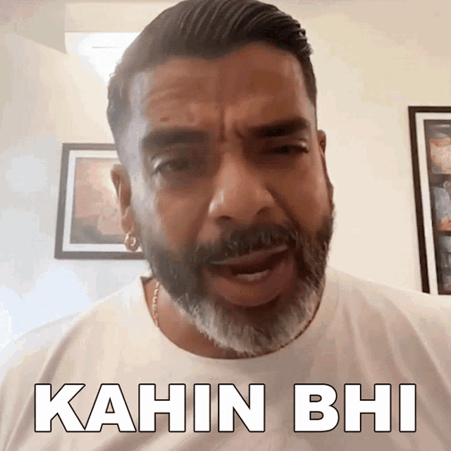 a man with a beard is wearing a white t-shirt that says kahin bhi