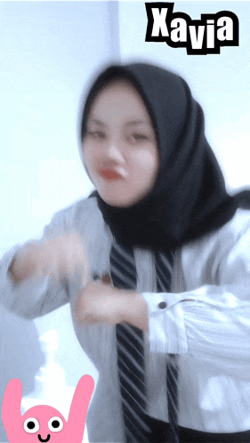 a woman wearing a hijab and a tie with the name kavia on the bottom right
