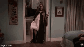 a woman in a cape is standing in a doorway holding a wand in a bedroom .