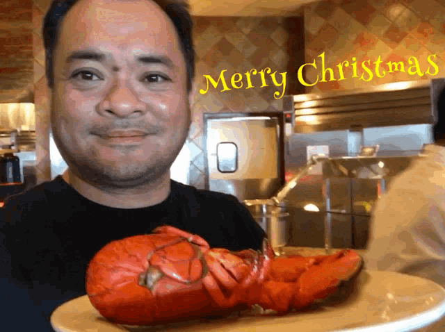 a man holding a plate of lobster with merry christmas written in yellow letters