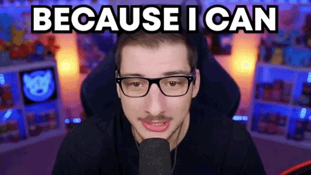 a man wearing glasses is sitting in front of a microphone with the words because i can behind him