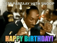 snoop dogg is wearing a suit and tie and holding a microphone .