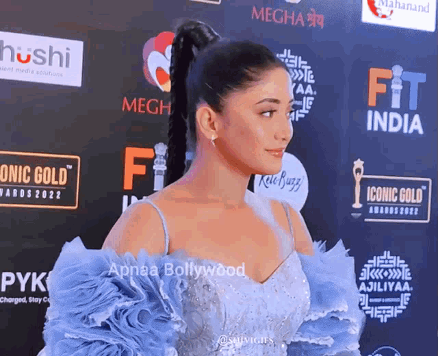 a woman in a blue dress stands in front of a red carpet that says fit india on it