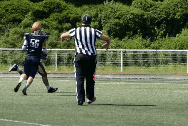 a football player with the number 56 on his jersey runs towards a referee