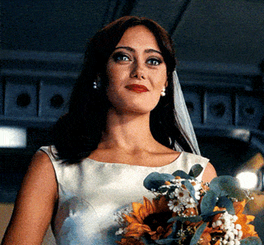 a woman in a wedding dress holds a bouquet of sunflowers