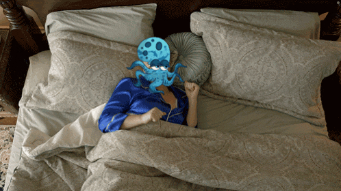 a woman is laying in bed with a blue octopus mask on her face