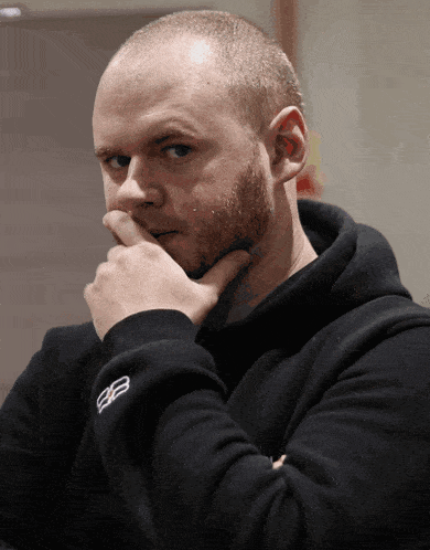 a man with a beard is wearing a black hoodie with the letters bb on it