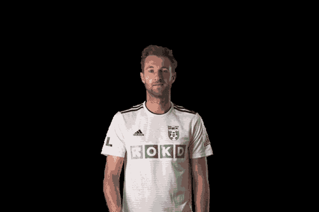 a man wearing a white shirt with rokd on the front