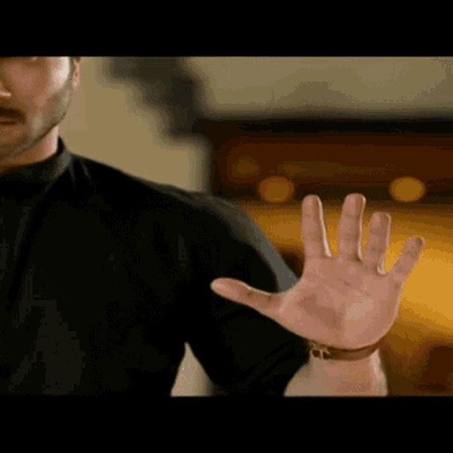 a man with a beard is wearing a black shirt and looking at the camera .