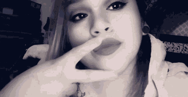 a black and white photo of a woman covering her mouth with her finger