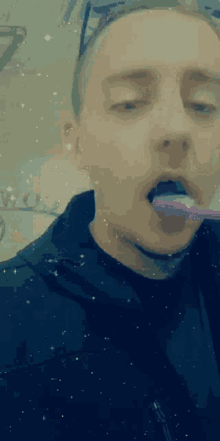 a young man is brushing his teeth with a pink toothbrush .