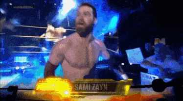 a shirtless wrestler named sami zayn is standing in a wrestling ring