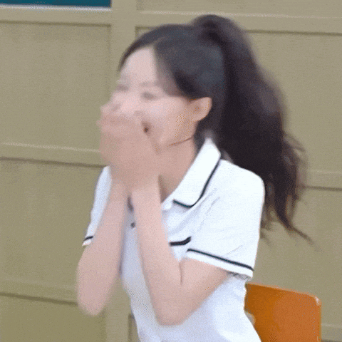 a girl in a school uniform is sitting in a chair with her hands on her face .