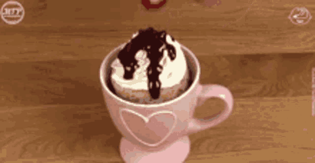 a pink cup with a cupcake and whipped cream in it