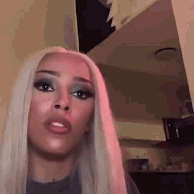 a woman with blonde hair and blue eyeshadow is making a funny face .