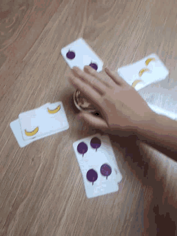 a person is playing a game with cards that have bananas and berries on them