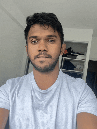 a man with a beard wearing a white shirt looks at the camera