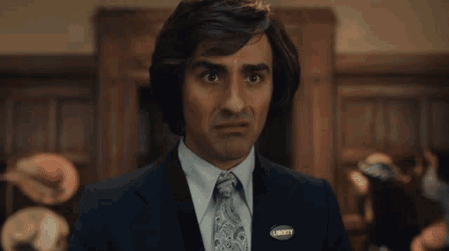 a man wearing a suit and tie has a liberty pin on his jacket