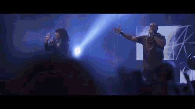 a man and woman singing into microphones on a stage