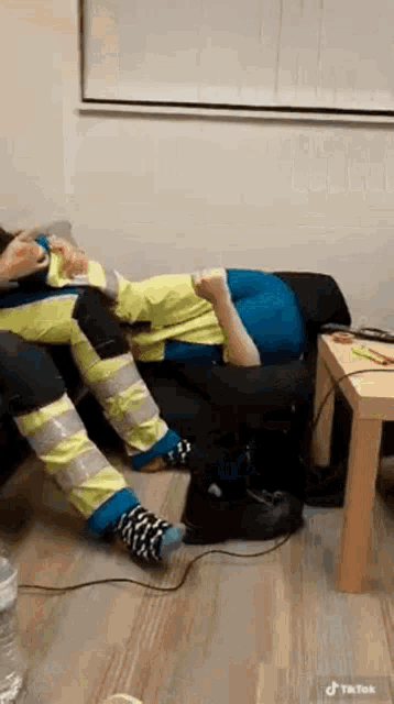 a person is laying on a couch with their legs wrapped in duct tape and socks .