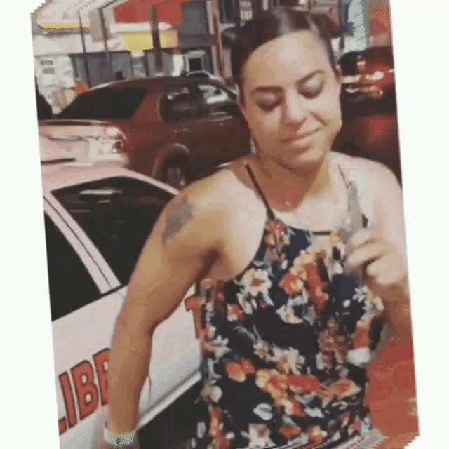a woman in a floral dress is standing in front of a car that says libre on the side