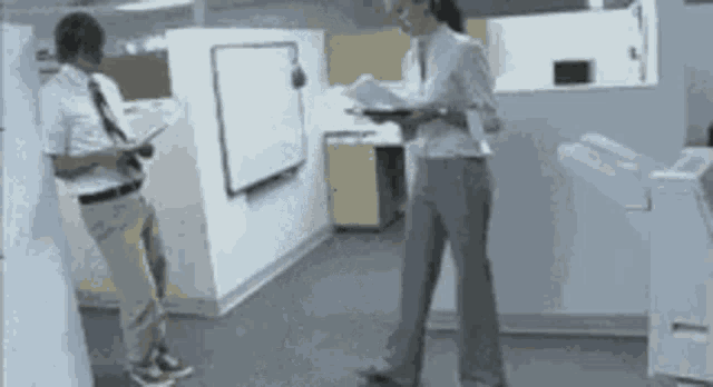 a man and a woman standing in a cubicle in an office